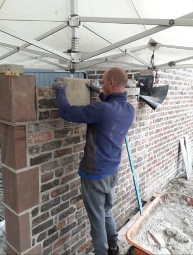 Hand carved date stone being built into garden wall in Grassendale, Liverpool