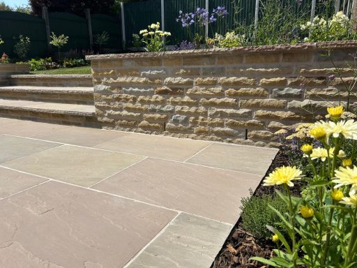 Yorkstone retaining wall, sandstone patio and steps in a landscaped garden designed by Dempsey Heritage in Ashton In Makerfield, Wigan.